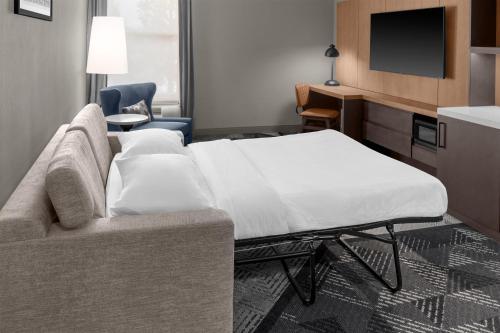 a room with a bed and a couch and a tv at DoubleTree by Hilton Dayton Fairborn in Fairborn