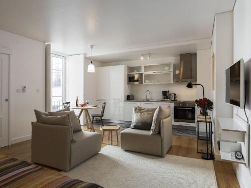 a living room with two chairs and a kitchen at LSA Baixa Castelo by Numa in Lisbon