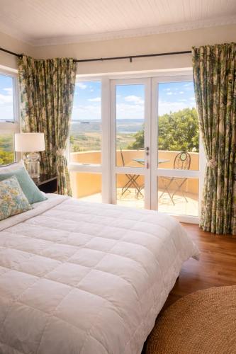 a bedroom with a large white bed and a balcony at The Gables Boutique Hotel in Chintsa