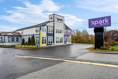 a building with a sign in front of a parking lot at Spark by Hilton Portland Airport Maine Mall in South Portland