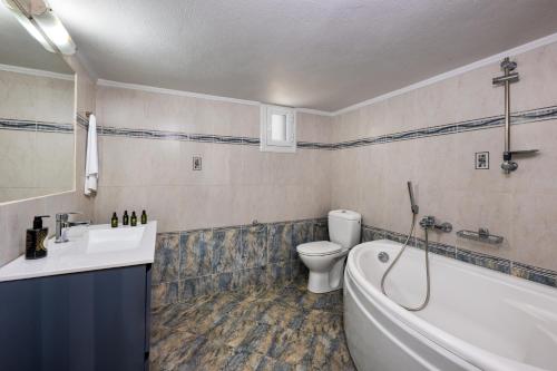 a bathroom with a tub and a sink and a toilet at Anchor House Santorini in Fira