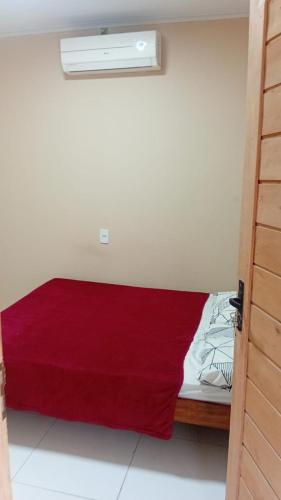 a room with a bed with a red blanket on it at Espaço Mãe Cecília in Paripueira