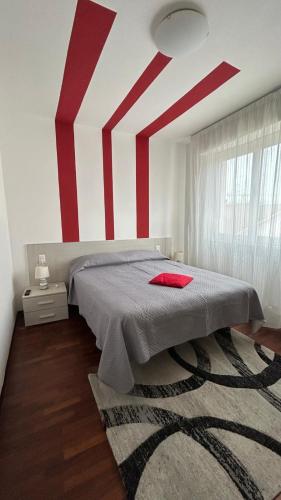 a bedroom with red and white stripes on the wall at Luminoso Appartamento al mare in Martinsicuro