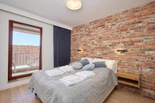a bedroom with a large bed with a brick wall at Nord-A Waterlane Island SPA in Gdańsk