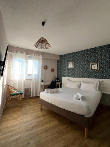 a bedroom with a large white bed and a chair at Logis Hôtel de la Bruyere in Pouzauges