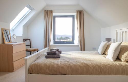 a white bedroom with a large bed with a window at 3 Carbost in Tole