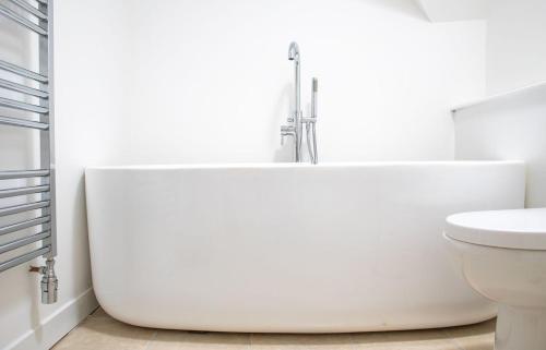 a white bathroom with a tub and a toilet at 3 Carbost in Tole