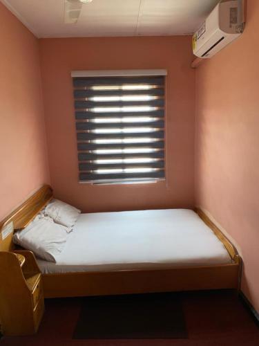 una piccola camera da letto con un letto e una finestra di Commander's Longterm Hotel a Achimota