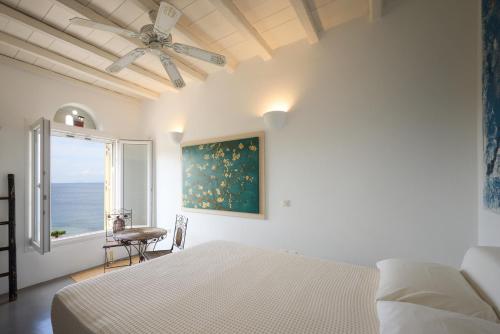 a white bedroom with a bed and a window at GL Villa in Agios Romanos