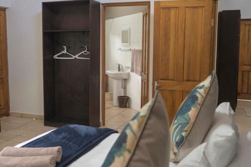 a room with a bed and a bathroom with a sink at Mazuri Bush Cottages in Hluhluwe