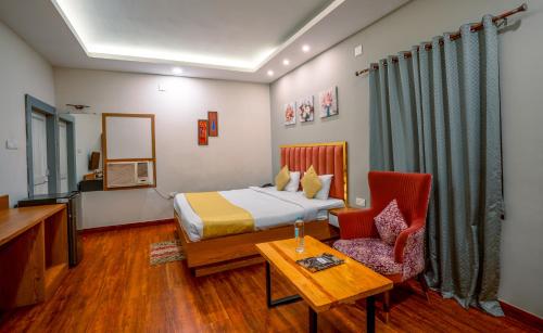 a hotel room with a bed and a table and chairs at Greenland Premium Hotel in Bhubaneshwar