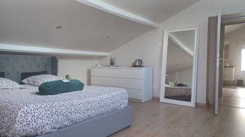 a white bedroom with a bed and a mirror at Les Deux Chambres Aucamville in Aucamville