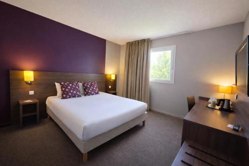 a hotel room with a white bed and a window at The Originals City, Hôtel Les Bruyères, Dax Nord in Castets