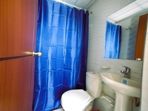 a bathroom with a blue shower curtain and a toilet at Bohemia Hotel in Tunja