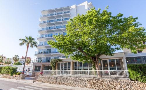 ein Gebäude mit einem Baum davor in der Unterkunft BLUESEA Cala Millor in Cala Millor