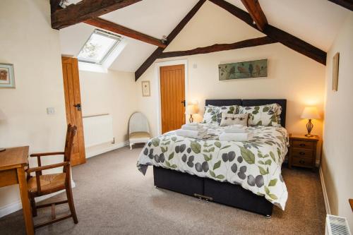 a bedroom with a bed and a desk and a window at The Granary at Little Howle Farm in Ross on Wye