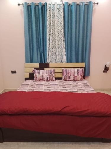 a bedroom with a red bed with blue curtains at Sariyal Homestay in Kandikhal