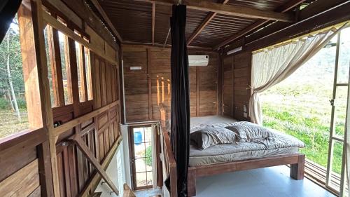 a bed in the inside of a room with windows at Em Cá Gỗ Farmstay in Phước Bình