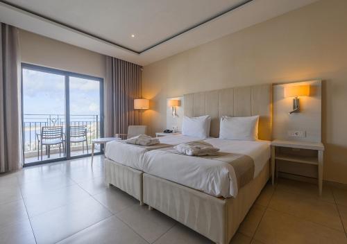 a hotel room with a large bed and a balcony at Maritim Antonine Hotel & Spa in Mellieħa