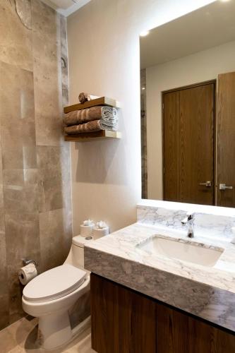 a bathroom with a sink and a toilet and a mirror at QUEEN ANGEL condo in Cozumel