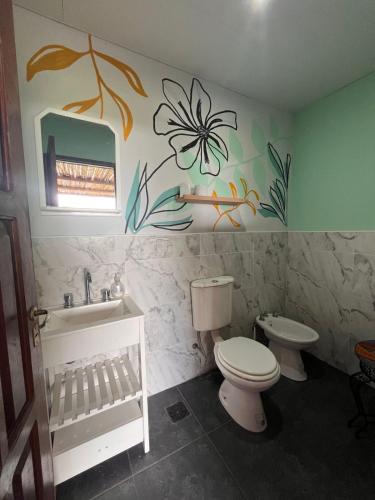 a bathroom with a toilet and a sink with a flower on the wall at Casa Azul Roldan in Roldán