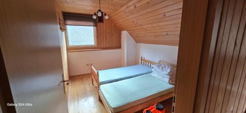 a small bedroom with a bed in a wooden room at Vila Two in Cârțișoara