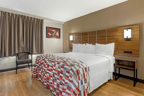 a hotel room with a large bed and a chair at Red Roof Inn Lumberton in Lumberton