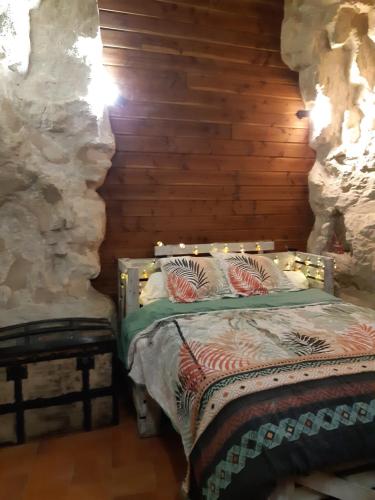 a bedroom with a bed in a stone wall at TROGLODYTE - La Grotte d'Auré in Le Puy-Notre-Dame