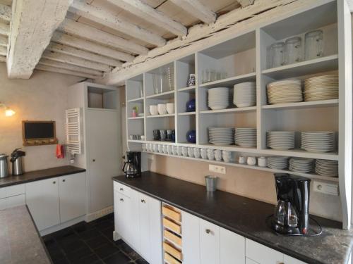 a kitchen with white cabinets and plates on shelves at Luxurious Farmhouse in Falaen with Sauna in Maredsous