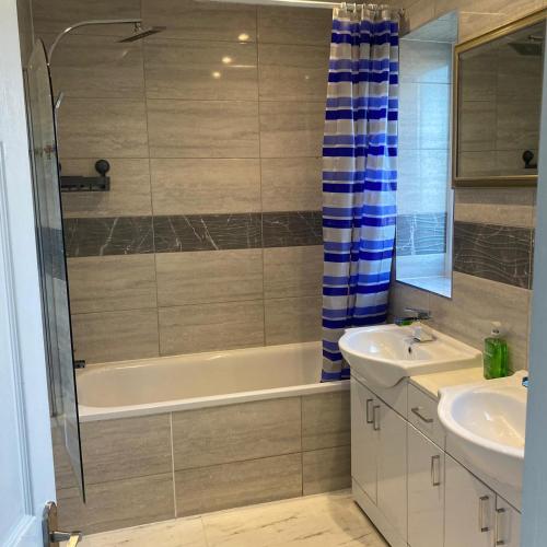 a bathroom with a tub and a sink and a shower at Robin's Accommodation in Wythenshawe