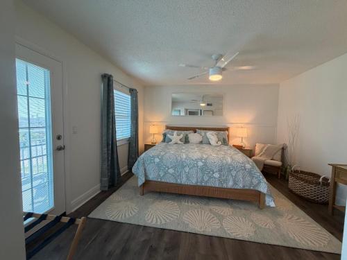 ein Schlafzimmer mit Bett, Stuhl und Fenstern in der Unterkunft Relaxing 1bd 1ba Condo - Ocean Front Complex in New Smyrna Beach in New Smyrna Beach