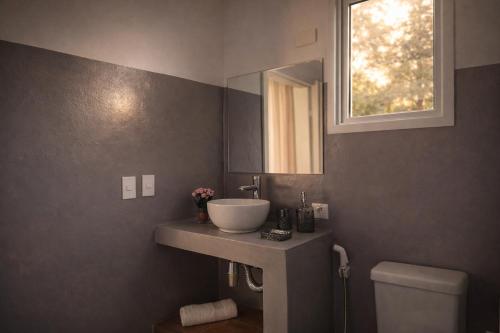 a bathroom with a sink and a toilet and a window at Pousada Águas do Alto in São Francisco Xavier