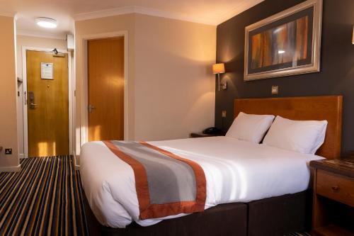 a hotel room with a large bed and a door at Weathervane Hotel by Greene King Inns in Stoke on Trent