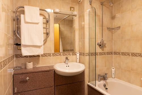 a bathroom with a sink and a mirror and a tub at Weathervane Hotel by Greene King Inns in Stoke on Trent