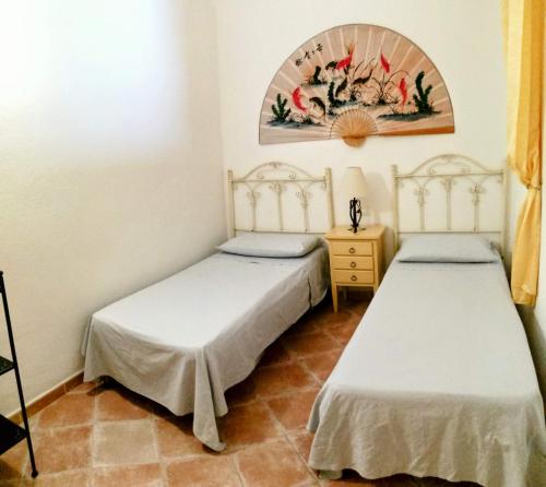 two twin beds in a room with a painting on the wall at Grazioso appartamento con tutti confort in Lu Lioni