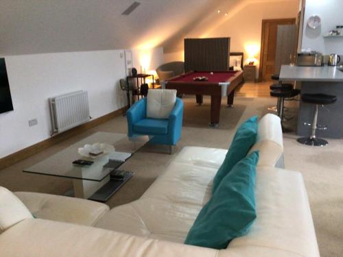 a living room with a white couch and a pool table at Luxury Studio Loft with Car Charging Point in Frizington
