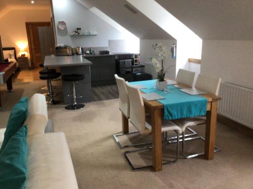 a living room with a table and chairs and a kitchen at Luxury Studio Loft with Car Charging Point in Frizington