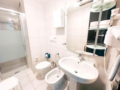 a white bathroom with a toilet and a sink at Hotel Britannia in Genoa