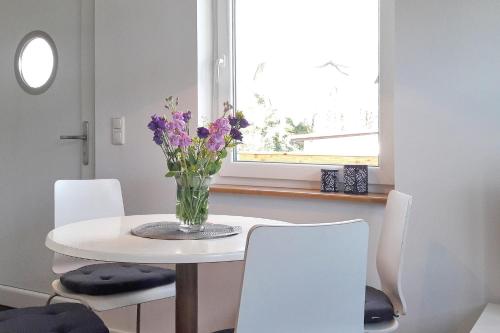 a white dining room table with a vase of flowers on it at Dobra in Lübbenau