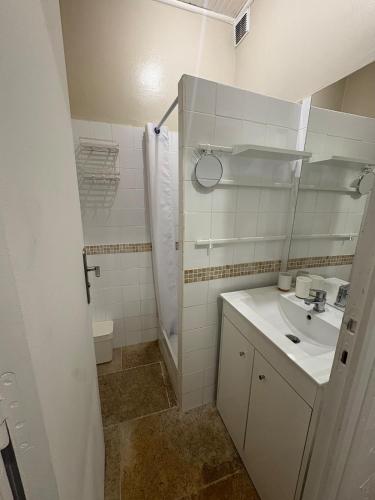 a white bathroom with a sink and a shower at Chez Fabienne Maison Fontvieille in Fontvieille