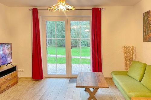 a living room with red curtains and a green couch at Laubhütte Baum 1 in Burg