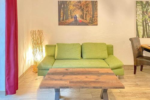 a living room with a green couch and a table at Laubhütte Baum 1 in Burg