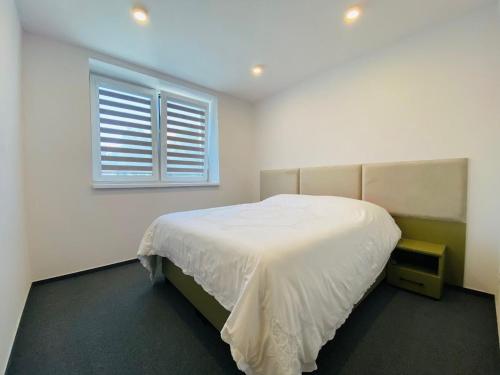 a bedroom with a white bed and a window at Apartman Alex in Liptovský Mikuláš