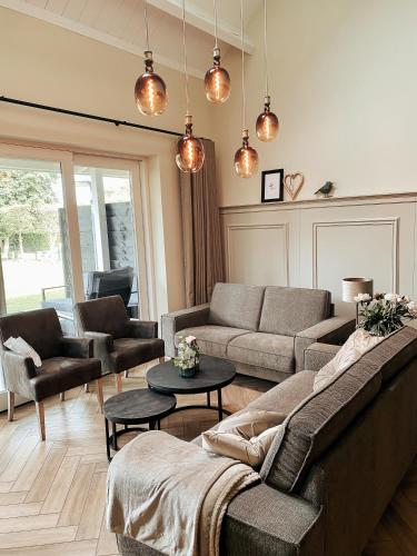 a living room with a couch and chairs and a table at De Stamhoeve, luxe vakantiehuis, rustig gelegen bij de Loonse & Drunense Duinen tussen 's Hertogenbosch en Tilburg in Biezenmortel