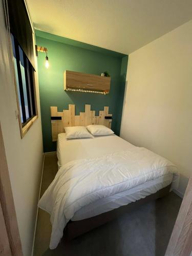a bedroom with a white bed with a green wall at L'ourson B2 in La Bresse