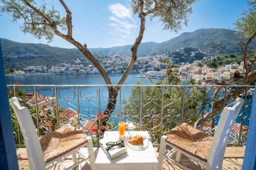ein Balkon mit Tisch und Stühlen und Blick aufs Wasser in der Unterkunft Artiki's Studios - Sea & Harbour View Apartments in Symi in Symi
