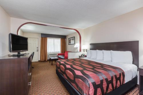a hotel room with a bed and a flat screen tv at Days Inn by Wyndham Pearl/Jackson Airport in Pearl