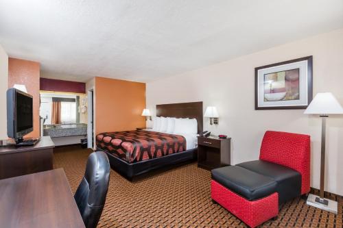 a hotel room with a bed and a chair at Days Inn by Wyndham Pearl/Jackson Airport in Pearl