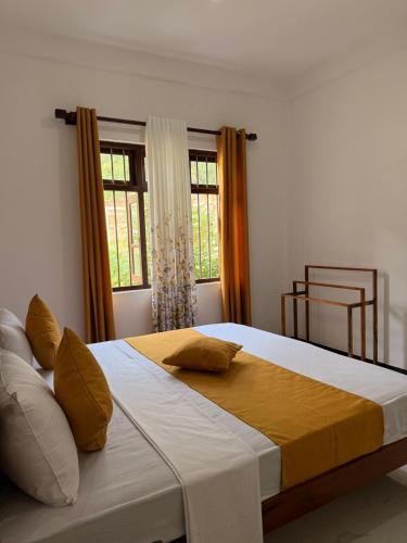 a large bed in a bedroom with two windows at Chara Bloom Hotel in Dickwella