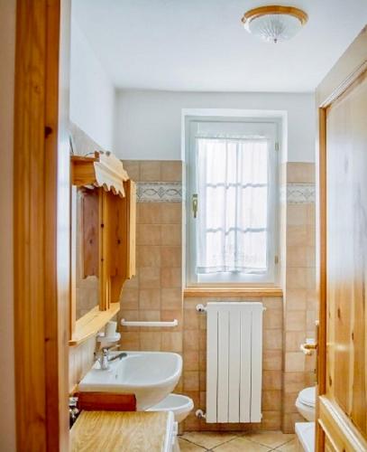 a bathroom with a sink and a toilet and a window at Ca' Maria - Casa in Scalve in Schilpario